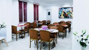 une salle à manger avec des tables, des chaises et des fleurs dans l'établissement Hôtel des Arcades, à Reims