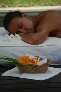 a man laying on a bed with a basket of flowers at The Park Samui in Choeng Mon Beach