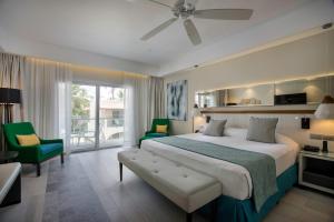 a bedroom with a large bed and green chairs at Catalonia Bayahibe - All Inclusive in Bayahibe