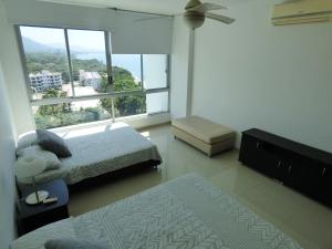 een slaapkamer met 2 bedden en een groot raam bij Costa Azul Suites 905 in Santa Marta