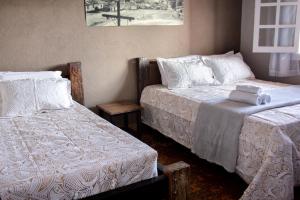 una camera con 2 letti con coperte e cuscini bianchi di Pousada Província a Lavras Novas