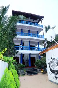 a blue and white building with a palm tree at Golden Surfer Beach Hotel in Tangalle