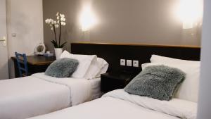 a hotel room with two beds with pillows at Hôtel des Arcades in Reims