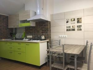 a kitchen with green and white cabinets and a table at Comfort place in the city centre in Ivano-Frankivsk