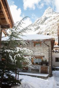 een huis in de sneeuw met een berg op de achtergrond bij Maison De Meuny in Courmayeur