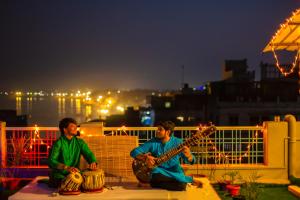 deux hommes sont assis sur une corne jouant de la guitare dans l'établissement Wander Station Varanasi, à Varanasi