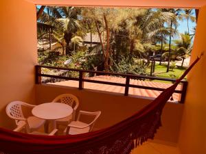 a hammock in a room with a table and chairs at Pousada Maraoka in Porto De Galinhas