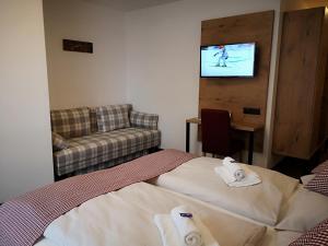 a room with two beds and a couch and a tv at Hotel Aschauer Hof z'Fritzn in Kirchberg in Tirol