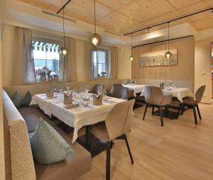 a restaurant with white tables and chairs and windows at Hotel Castel - pure Lebensfreude in Serfaus