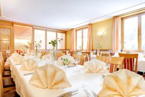 ein Esszimmer mit weißen Tischen, Stühlen und Fenstern in der Unterkunft Hotel Gasthof KREUZ in Sonntag