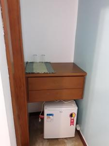 uma cómoda e um frigorífico debaixo de uma mesa num quarto em Pousada Casa das Rosas em Búzios