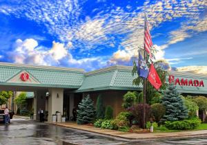 a building with american flags in front of it at Ramada by Wyndham Alpena in Alpena