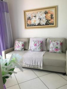 a couch with pink and white pillows in a living room at Residencial Viamar in Praia Grande