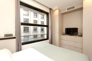 パリにあるApartment Opéra / Galeries Lafayetteの窓、ベッド、テレビが備わるベッドルーム1室が備わります。