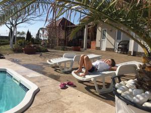 a man laying on a lawn chair next to a swimming pool at Villa Diana Mini in Karolino-Buhaz