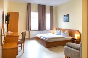um quarto de hotel com uma cama e uma cadeira em Hotel Thüringer Hof em Jena