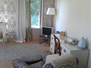 a living room with a tv and two chairs at Cornerstones Guest House in Sale