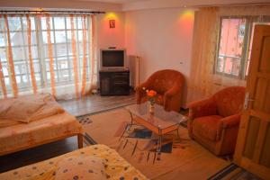 a living room with two chairs a table and a tv at Casa Parvu in Lunca Mare