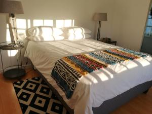 een slaapkamer met een groot bed met witte lakens en kussens bij Almond Cottage Bed & Breakfast in Somerset West
