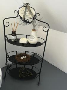 a black shelf with a clock and vases on it at Almond Cottage Bed & Breakfast in Somerset West