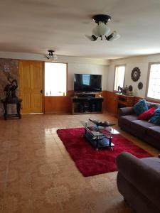 Residencial mi Casa في أولموي: غرفة معيشة مع أريكة وسجادة حمراء