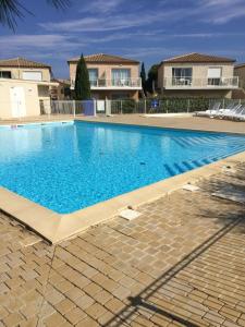 a large blue swimming pool in front of some houses at T 3 appart les jardins du phœbus in Gruissan