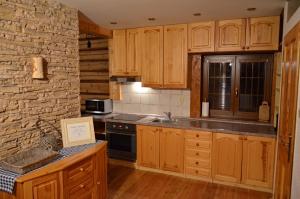 a kitchen with wooden cabinets and a stone wall at Chata Filipsky in Ždiar
