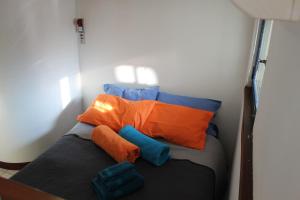 uma pequena cama num quarto com almofadas laranja e azul em LA SERRA 211 em Ivrea