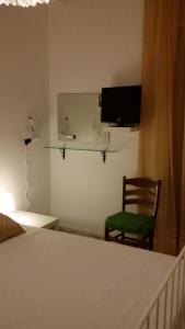 sypialnia z łóżkiem, krzesłem i telewizorem w obiekcie B&B Metropolitan Taranto w mieście Tarent
