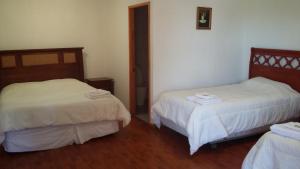 Habitación con 2 camas y sábanas blancas. en Hotel Nogal, en Constitución