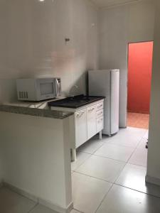 a kitchen with a counter with a microwave and a refrigerator at Flat Thermas Olimpia - 300 metros do Thermas dos Laranjais in Olímpia