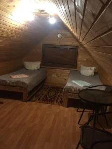 a room with two beds and a table in a attic at Guesthouse Kolo Druziv in Tatariv
