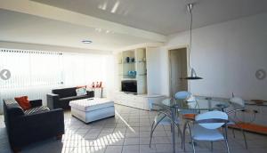 a living room with a couch and a glass table at Cobertura Duplex perto do mar, piscina, linda vista, 03 garagens, churrasqueira in Guaratuba