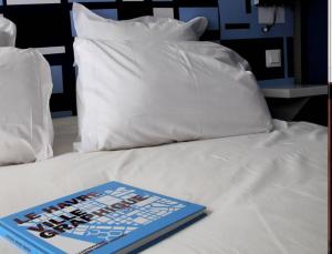 a book sitting on top of a bed with pillows at Escale Quai George V in Le Havre