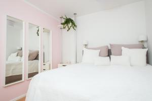 a white bedroom with a white bed and a mirror at Cute & Cozy in Wiesbaden