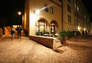 a couple of people walking past a building at night at Hotel Le Macine in Vittorio Veneto