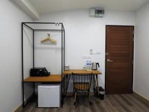 Habitación con escritorio, mesa y puerta en The Ghee House, en Chiang Mai