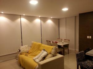 een woonkamer met een bank en een gele deken bij quarto social privado ap compartilhado in Capão da Canoa