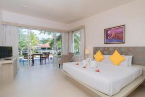 - une chambre avec un grand lit blanc et une télévision dans l'établissement The Briza Beach Resort, Khao Lak SHA Extra Plus, à Khao Lak