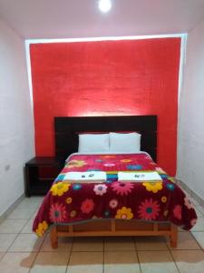 een bed met een rood hoofdeinde en een kleurrijke sprei bij Hotel Boutique Otomi cerca de Tolantongo in Cardonal