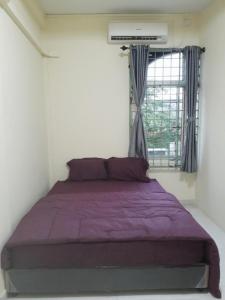 a bedroom with a purple bed in front of a window at Jakson Homestay in Batam Center