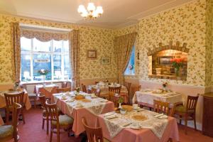 comedor con mesas y sillas y papel pintado de color amarillo en Midway Guest House, en York