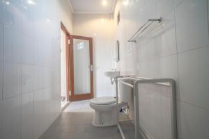 a white bathroom with a toilet and a sink at Baba Homestay in Ubud