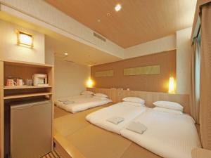 two twin beds in a room with a kitchen at Hotel Nikko Narita in Narita