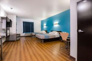 a hotel room with two beds and a blue wall at Motel 6 Poplar Bluff, MO in Poplar Bluff