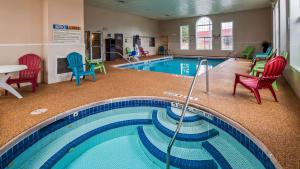 a swimming pool with chairs and a table and chairs at Best Western Crown Inn & Suites - Batavia in Batavia