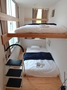 a bedroom with two bunk beds and a chair at 駐車場無料 Nagoya Hostel The Three Smiles Free Car Park in Nagoya