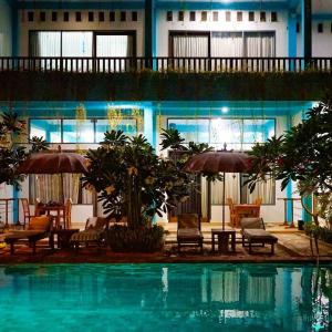 a pool with chairs and umbrellas in front of a building at Villa Rembulan in Gili Trawangan