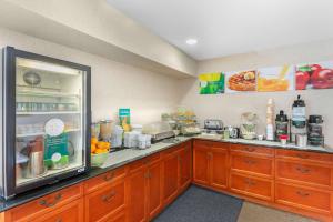 a kitchen with wooden cabinets and a large refrigerator at Quality Inn & Suites Oceanside Near Camp Pendleton in Oceanside