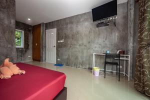 a bedroom with a red bed and a tv on a wall at Maenam Villa Hotel in Mae Nam